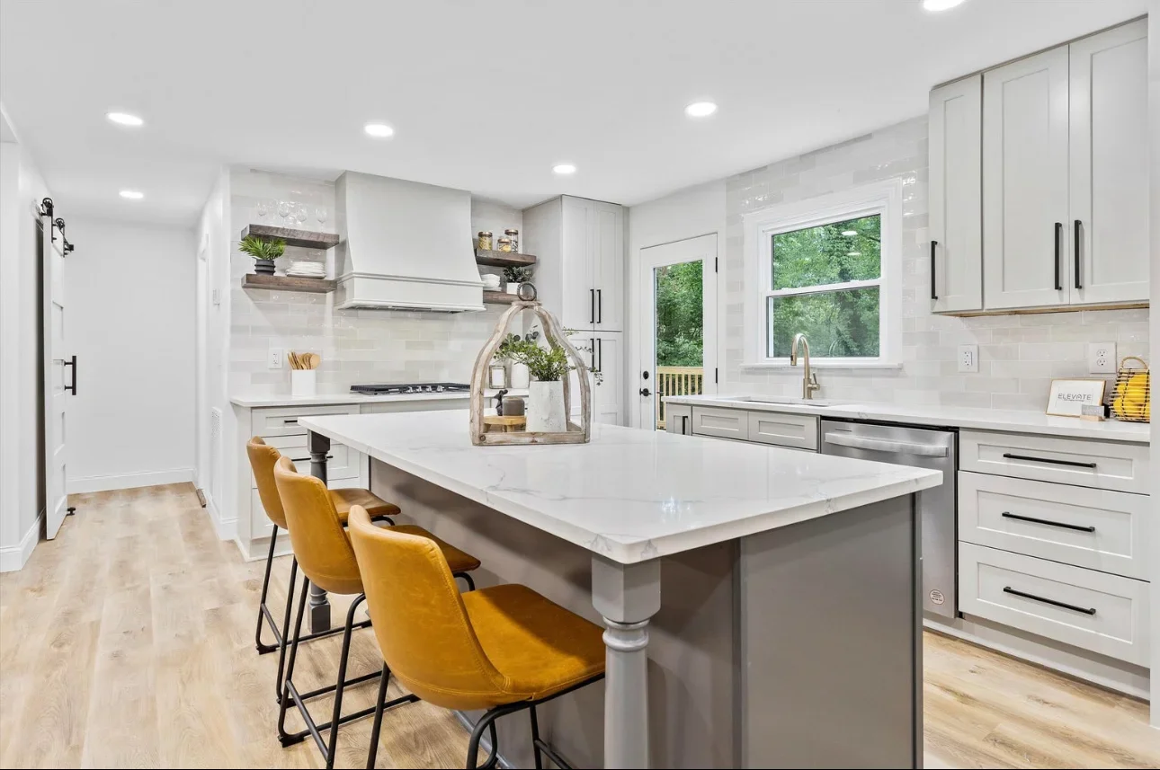 White kitchen with quartz island, shaker cabinets, stainless steel appliances, and subway tile backsplash