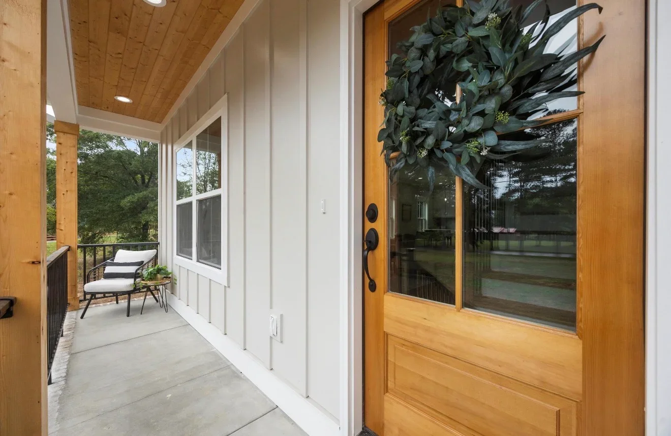 Screened porch with knotty pine ceiling, white walls, large windows, and wood entry door
